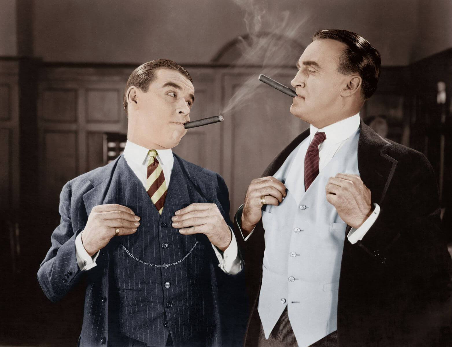 Two men in fancy suits smoking cigars by Everett Collection via Shutterstock